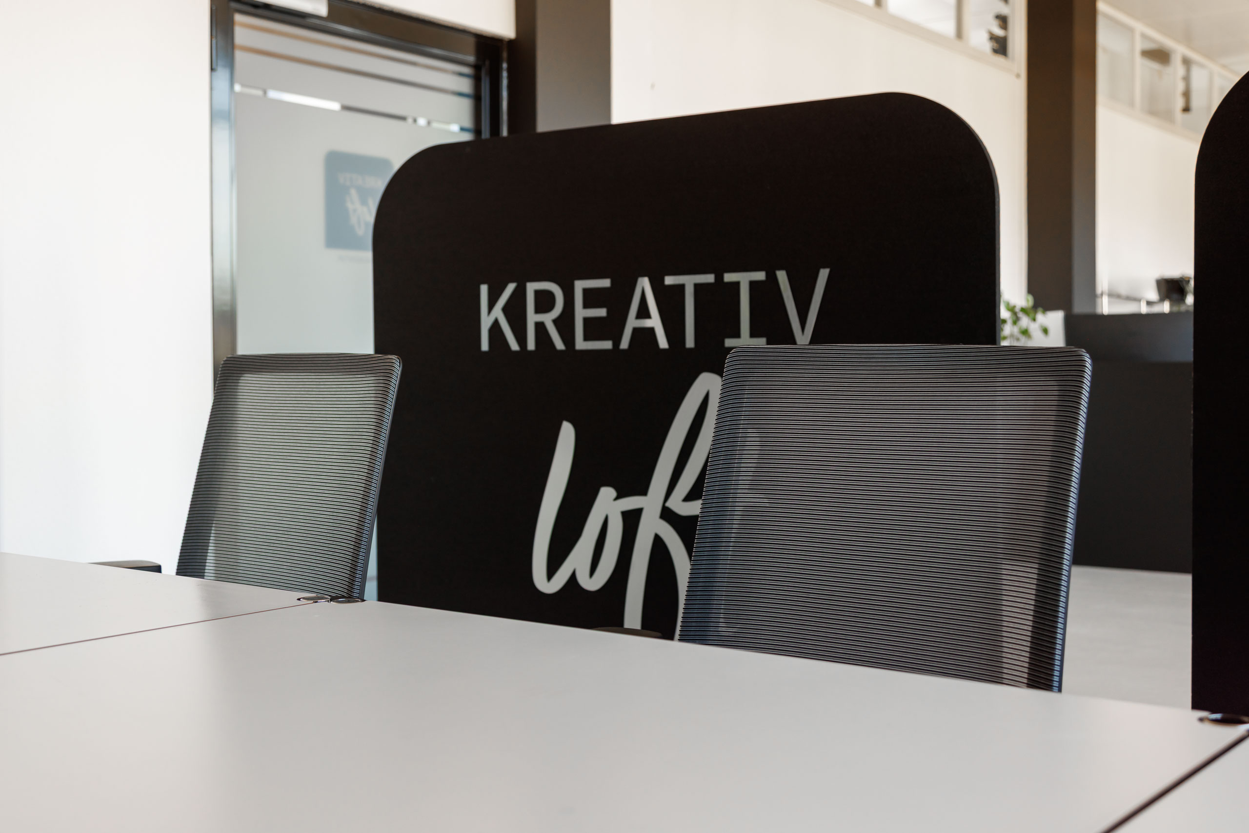 Sitzungsbereich, Kreativloft GmbH Werbeagentur Solothurn Moderner Sitzungstisch mit Stühlen und Akustikwand mit Kreativloft Logo in den Büroräumlichkeiten der Kreativloft GmbH Werbeagentur Solothurn.